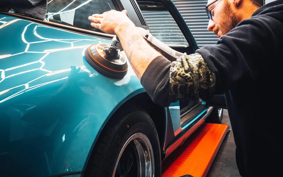 Inhaber von ShinyDrive poliert den Lack eines Sportwagens mit der Poliermaschine in Wuppertal